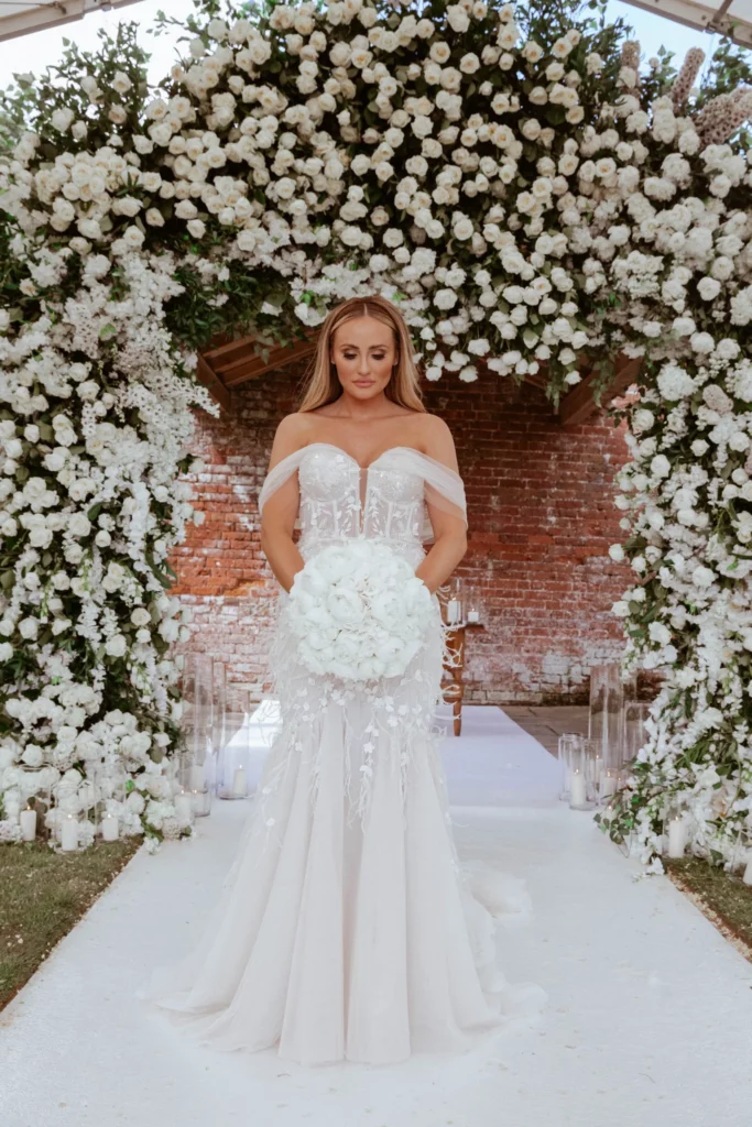 Event Planner: Charlotte Elise. Luxury bridal dress white open shoulders, white bridal bouquet, white wedding arch.