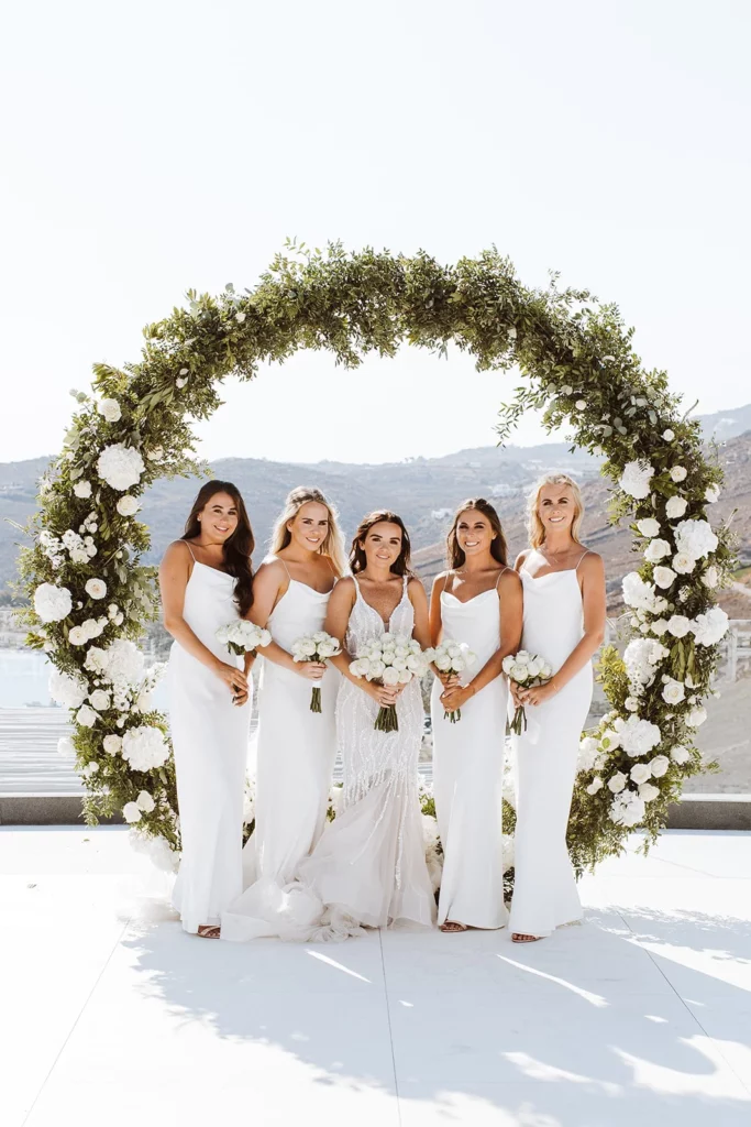 Event Planner: Charlotte Elise. Wedding on the coast, wedding view, round foliage wedding aisle, frame, white bridesmaid dresses, destination wedding.