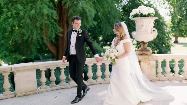 Camilla Joy Photography. Bride and groom holding hands in the balcony of the castle.