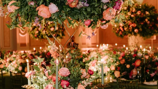 Event Planner: Kristina Kempton. Bright floral arrangement, large flower pots on wedding tables, forest green table and chairs, rose, pink, orange, red flowers.