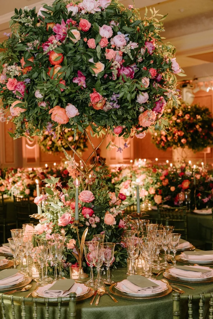 Event Planner: Kristina Kempton. Bright floral arrangement, large flower pots on wedding tables, forest green table and chairs, rose, pink, orange, red flowers.