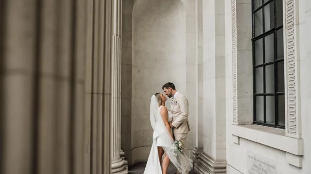 Photographer: Katie Rogers. Modern bride and groom, town hall wedding ceremony, short bridal dress, beige grooms suit.