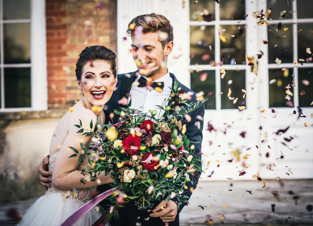 Event Planner: My Wedding Fixer. Bride and groom, gold confetti, bright red and purple bridal bouquet.