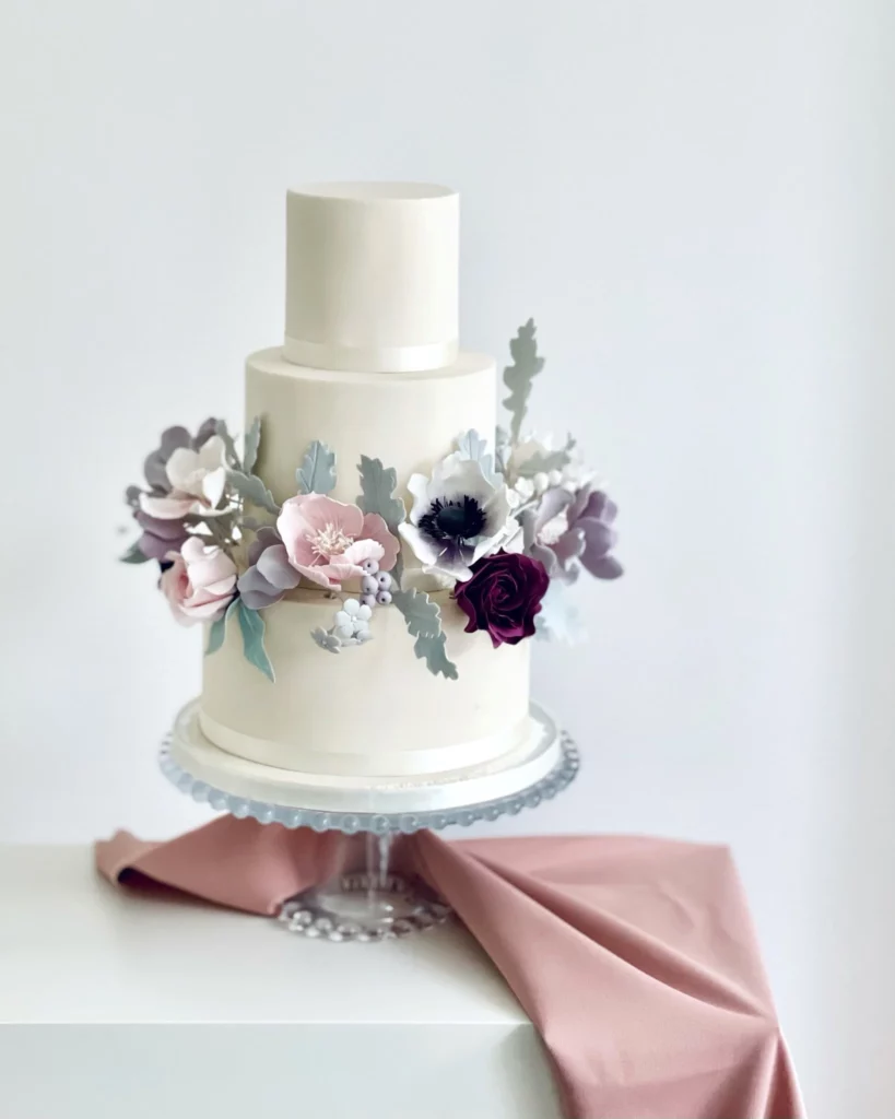 Cake Designer: Rosalind Miller Cakes. White wedding cake 3 tiers with lilac and purple edible sugar flowers.