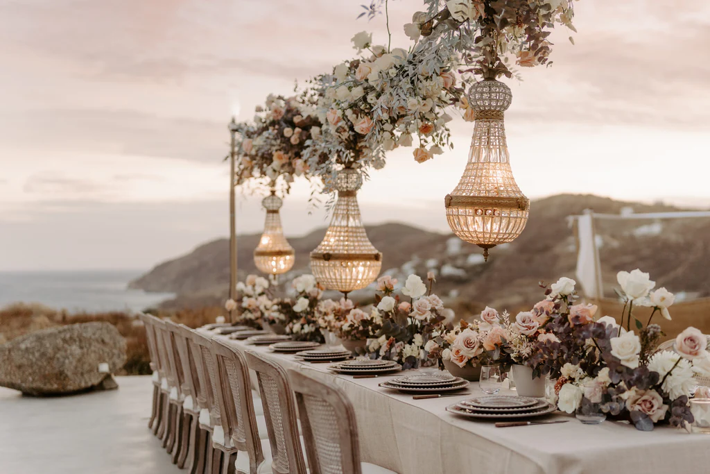 Event Planner: The Stars Inside. Elopement in Europe, coast, rocks and ocean view, Italian style, chandeliers, burnt orange, pastel dusty rose, beige wedding table.