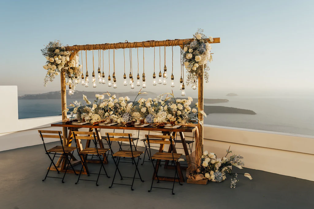 Event Planner: The Stars Inside. Elopement, micro wedding, destination wedding, small wedding table decor, dusty blue and white flowers, wooden table and chairs, hanging lightbulbs over table wedding.