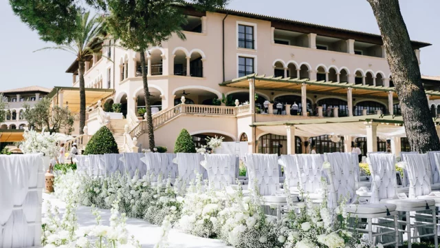 Event Planner: Tracy Lavin Events. Spain destination wedding, white wedding ceremony, white floral arrangement, chairs, wedding aisle.