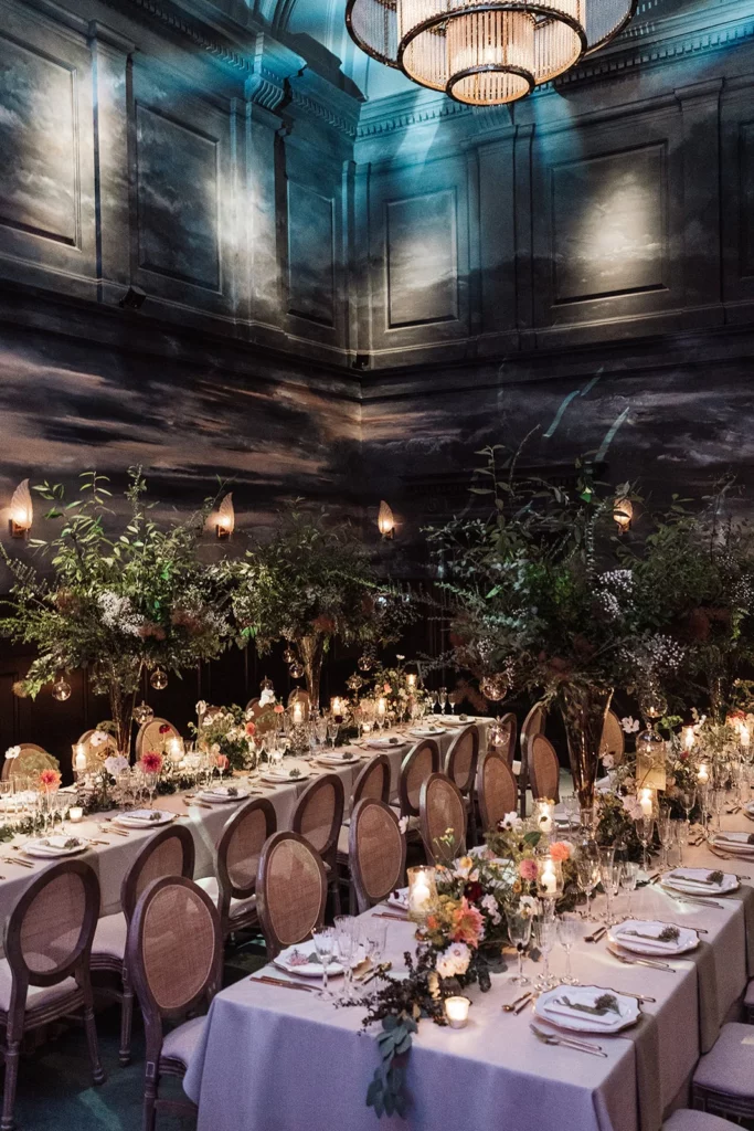 Event Planner: Emma Westacott. Dramatic wedding venue, hall, black walls, dark moody floral arrangement wedding table.