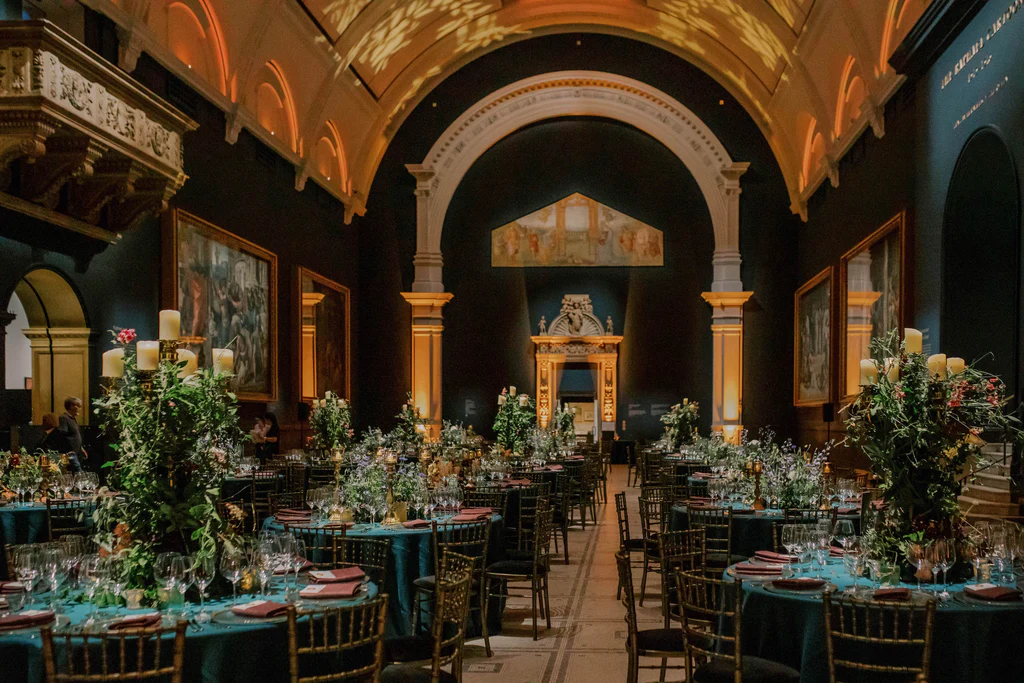 Florist: Wild At Heart. Dramatic wedding dinner reception, green tables, gold chairs, foliage and candles.